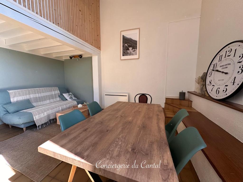a living room with a wooden table and a clock at Edelweiss in Apchon