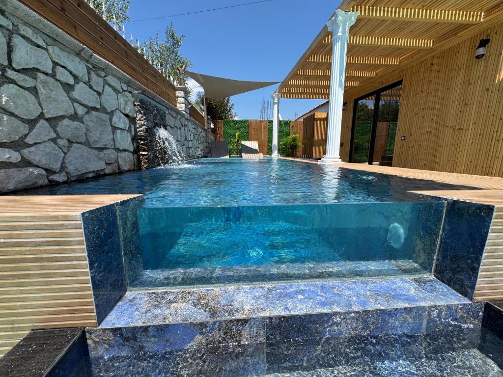 a swimming pool in a house with a stone wall at Infinity Suites Pushi in Ksamil