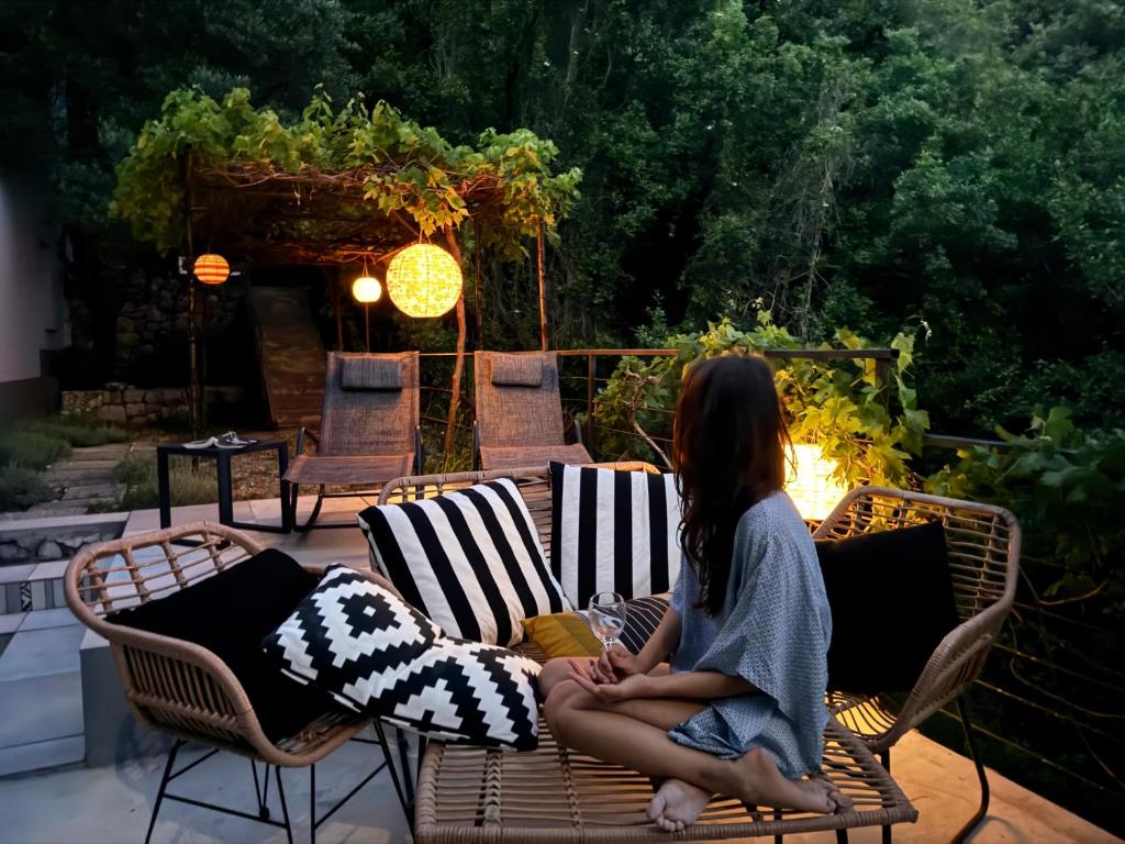 a woman sitting on a chair on a patio at Quercus Apartment in Stara Baška