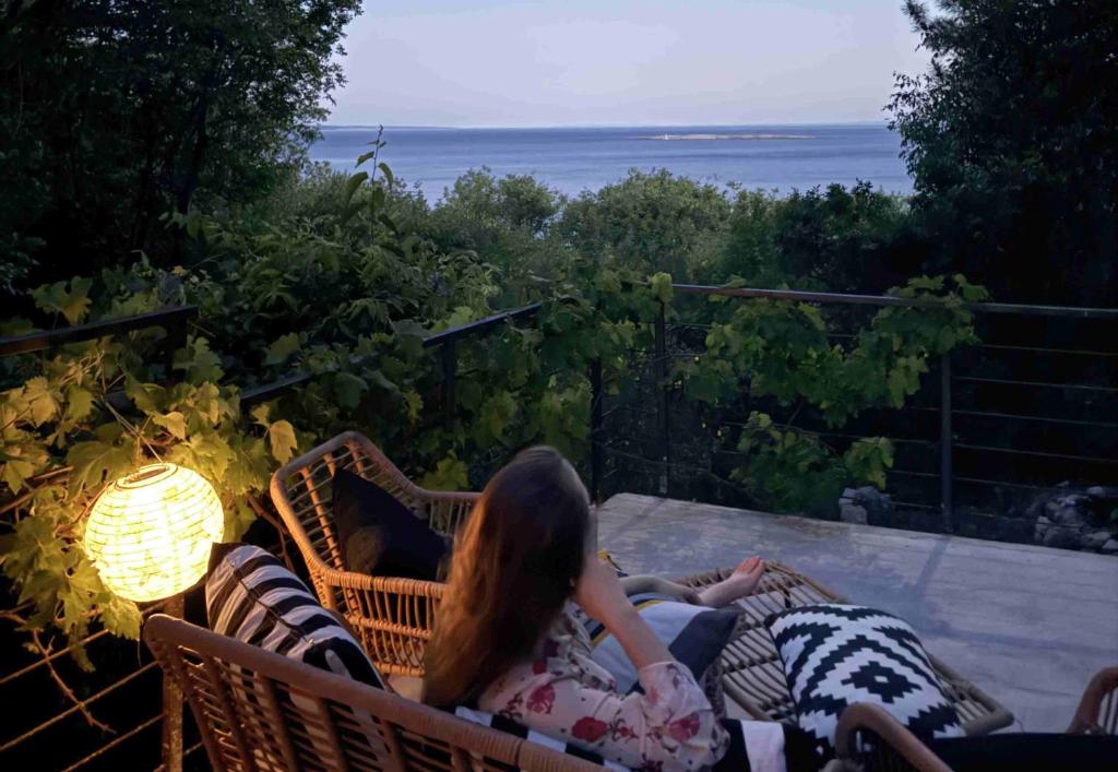 a woman laying in a wicker chair on a patio at Maramare Pinus in Stara Baška