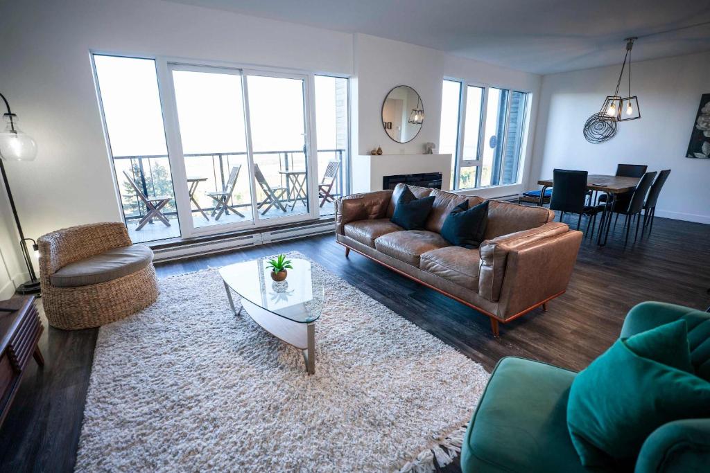 a living room with a leather couch and a table at 310 - Luxury Condo The Serenity - View and Pool in Baie-Saint-Paul