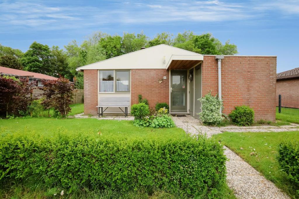a small brick house with a grass yard at Rekerlanden 187 in Schoorldam