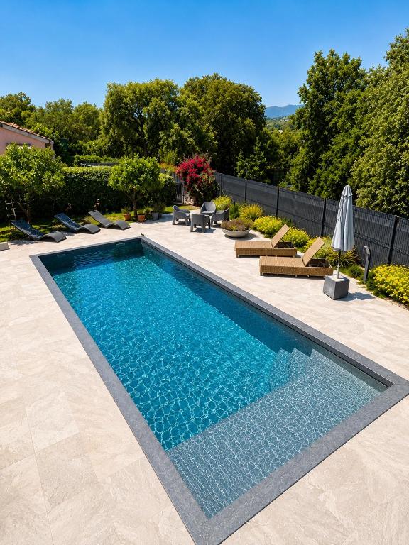 a swimming pool in a yard with chairs and umbrellas at LOGEMENTS ACCÈS PISCINE - T2 Résidence Serena in Cuttoli-Corticchiato