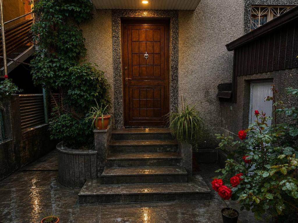 a house with a wooden door and stairs in the rain at Sunshine Boutique Hostel in Yerevan