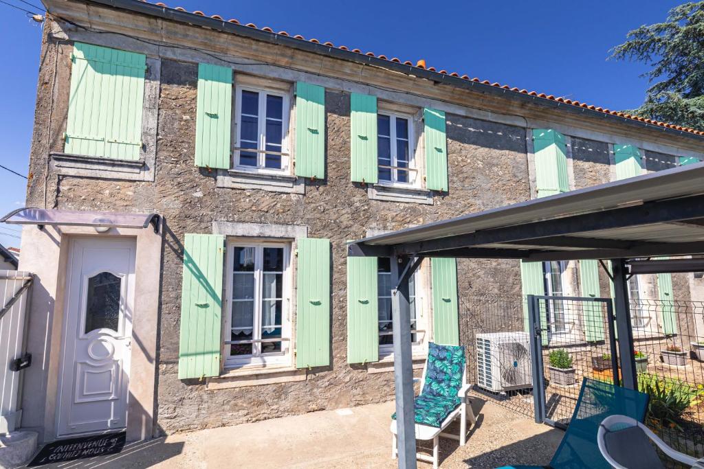 an old brick building with green shutters and a chair at Chez Catherine Et Gérard in Tonnay-Charente