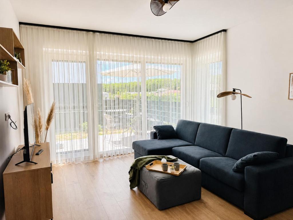 a living room with a blue couch and a large window at Small Garden Apartman in Sárvár