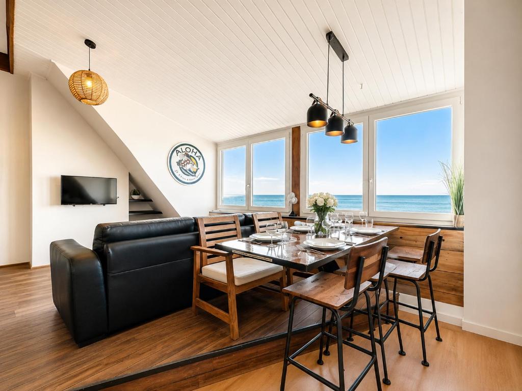 a dining room with a table and chairs and a couch at Villaloha - Appartement avec terrasse in Bray-Dunes