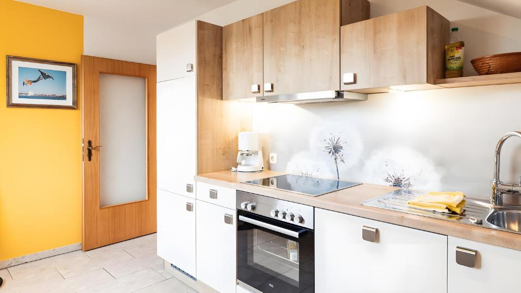 a kitchen with white cabinets and a sink at Haus an der Pferdekoppel Nr 2 in Fehmarn