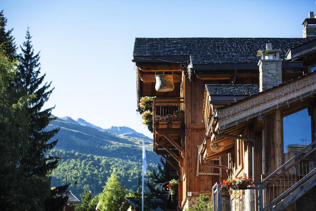 a wooden house with a balcony and mountains in the background at La Bouitte - Hôtel Relais & Châteaux in Saint-Martin-de-Belleville