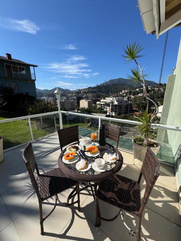 a table and chairs on a balcony with food on it at Aconchegante casa com piscina e lazer completo in Teresópolis