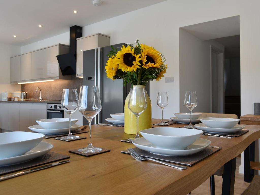 a wooden table with plates and glasses and a vase with sunflowers at Brameley in Cheriton Bishop