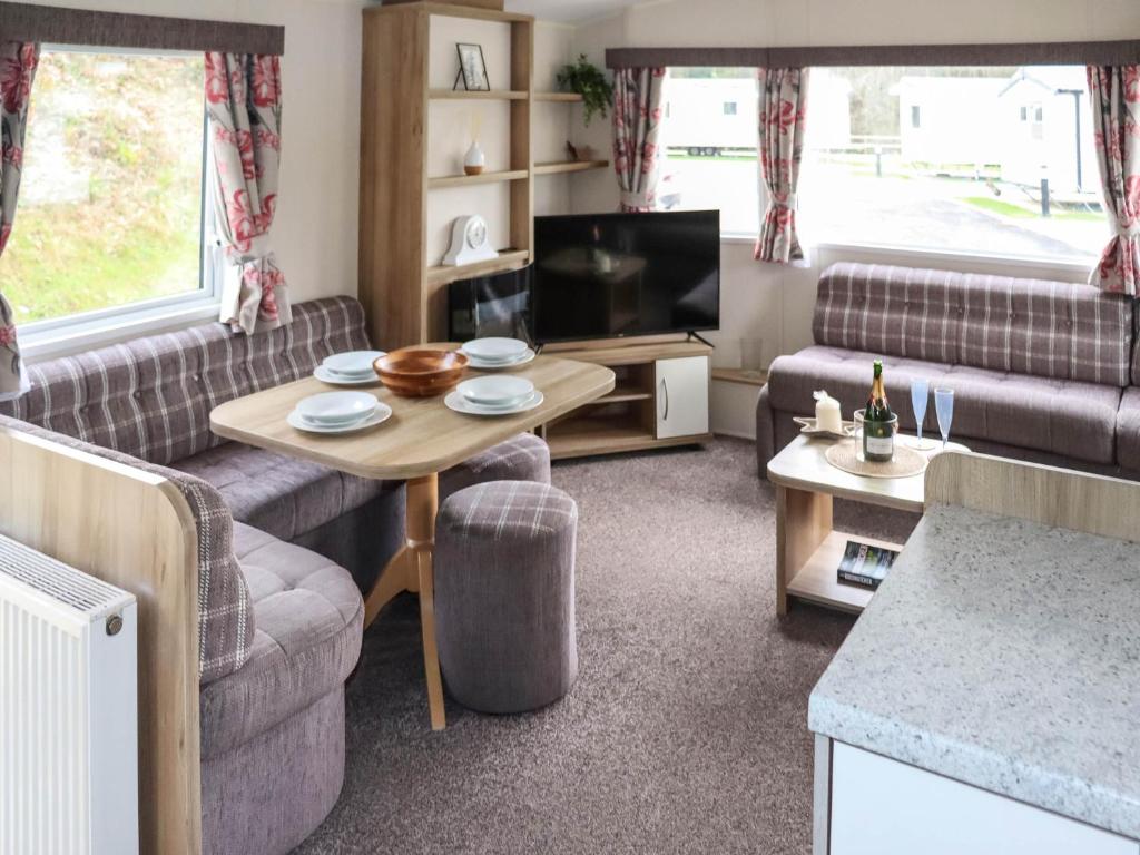 a living room with couches and a table and a tv at Acorn 1 - Ukc8213 in Pendine