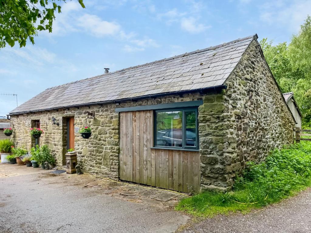 an old stone building with a large window at Silk Hill Stables in Whaley Bridge
