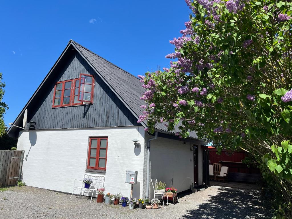 a white house with a black roof and red windows at Boots and Bikes B&B in Neksø