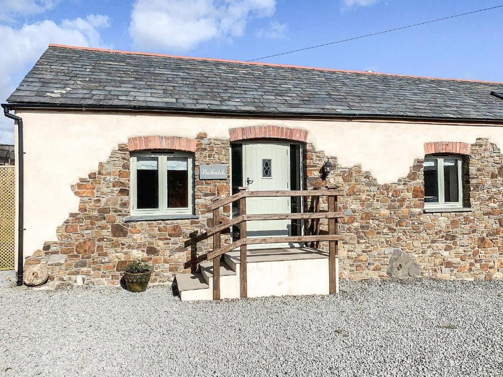 a small stone cottage with a wooden porch at Nuthatch Barn in Pancrasweek