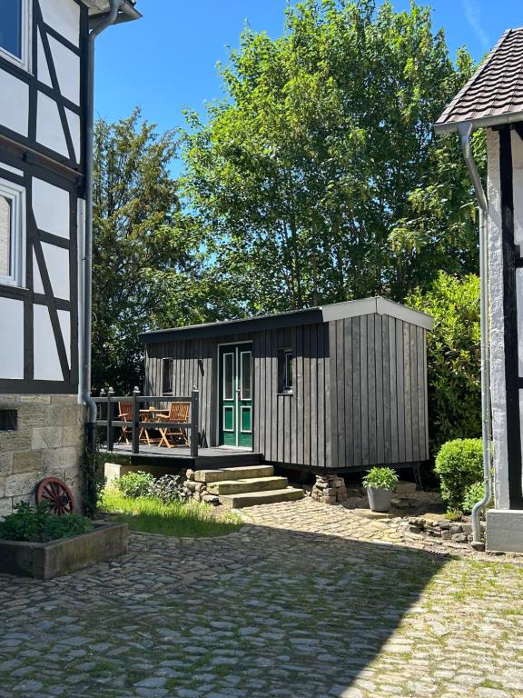 a small cabin with a green door in a yard at Zirkuswagen im Gutshof in Lutterberg
