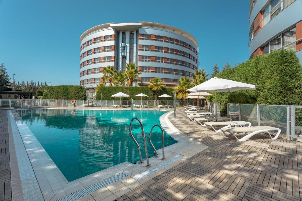 a swimming pool with chairs and umbrellas next to a building at Hotel Abades Nevada Palace in Granada