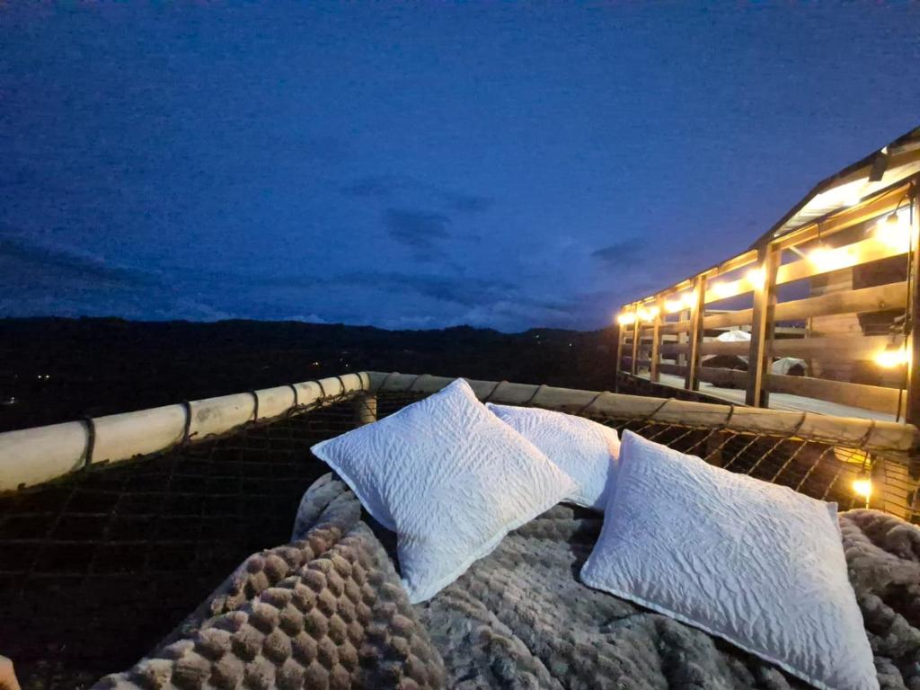 a bed with pillows on a rooftop at night at Cabaña del Sol in Medellín