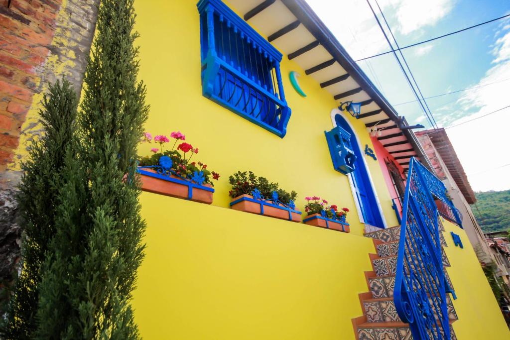 a yellow wall with blue windows and potted plants at Casa Amarilla in San Gil