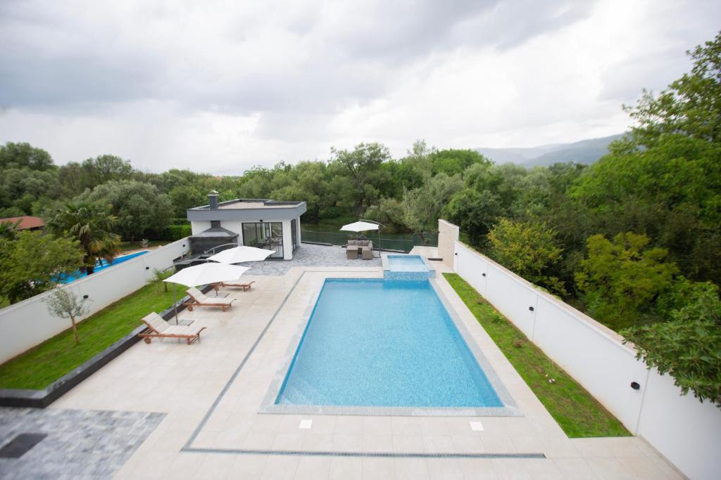 a swimming pool with chairs and umbrellas on a building at Villa H in Blagaj