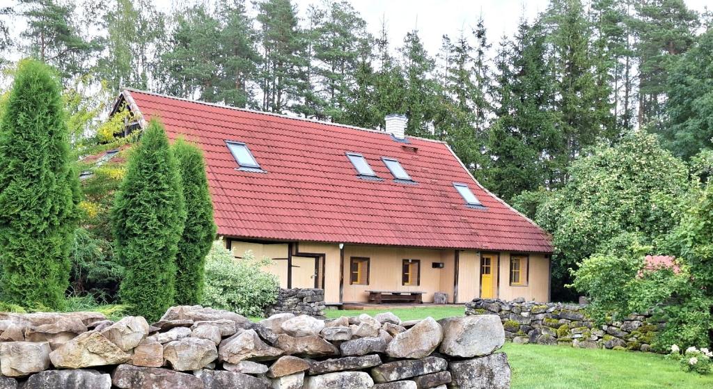 a house with a red roof and a stone wall at Sika Holiday Houses in Hellamaa