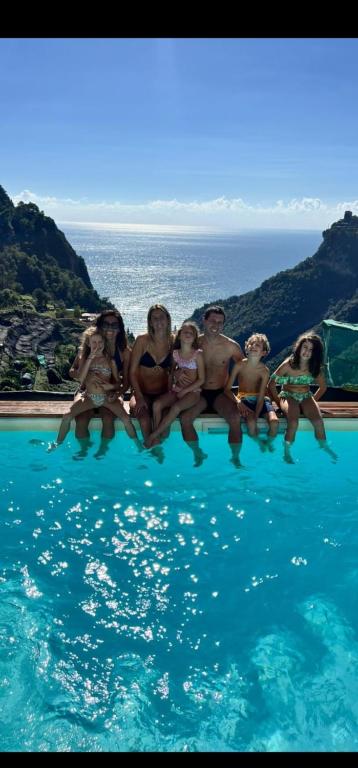 a group of people sitting on the edge of a swimming pool at Admiring Amalfi in Scala