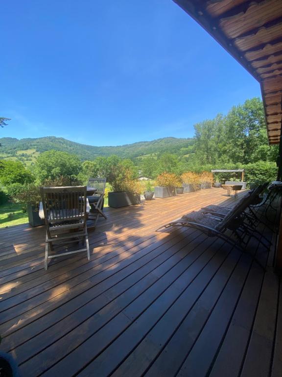 a deck with benches and a table and chairs on it at Chambre & grande Terrasse Privées, Vue Montagne - Chalet Bella Rosa in Argein