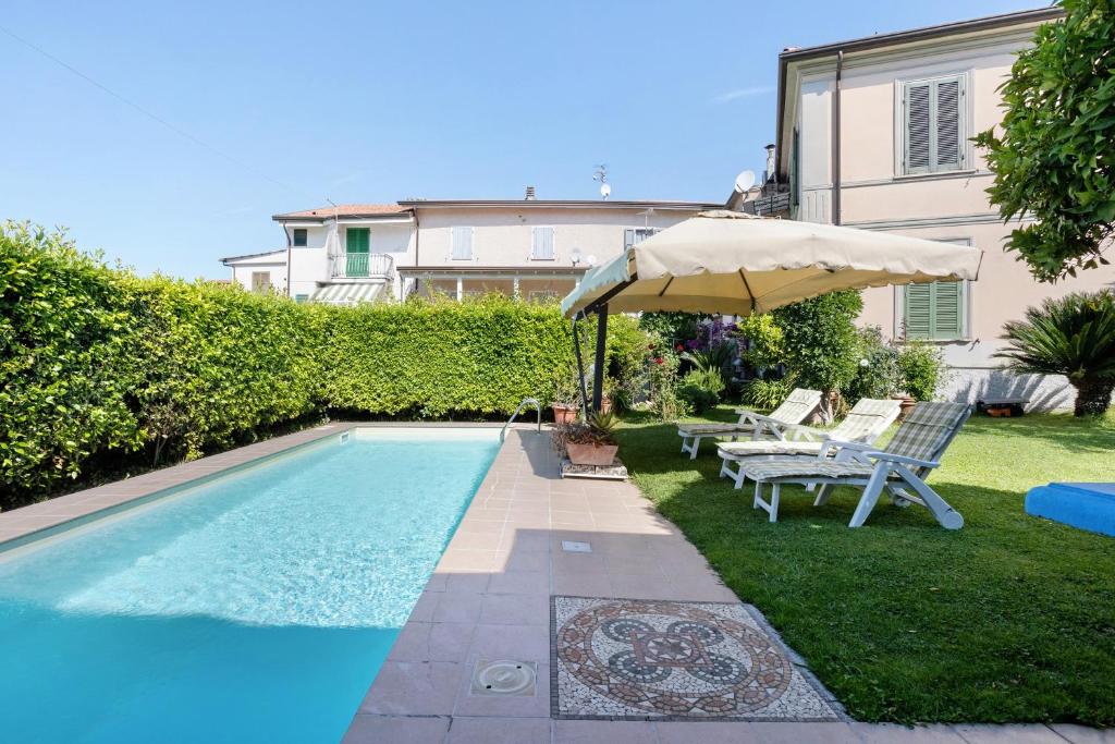 a swimming pool with an umbrella and a table and chairs at Il Giardino di Magò in Massa