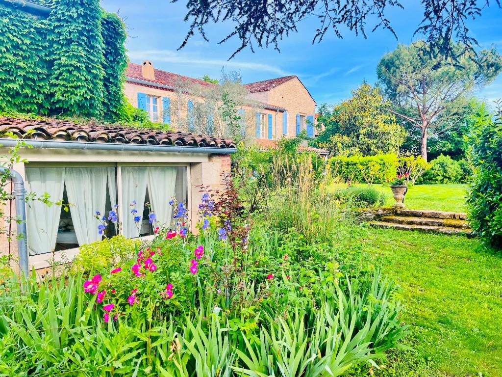 a garden with flowers in front of a house at Le Relais des Anges in Mercuès