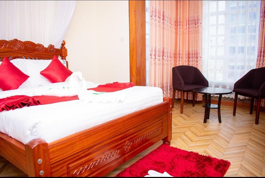 a bedroom with a bed with red pillows and a window at Hillpark Hotel in Eldoret