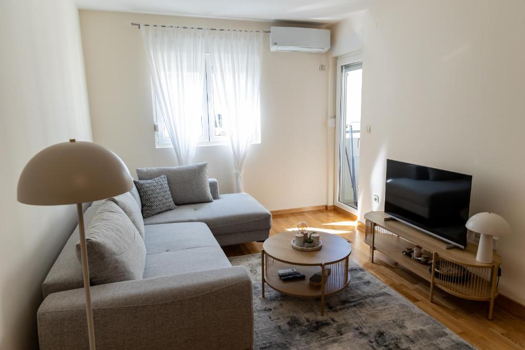 a living room with a couch and a tv at Lumi Apartment in Podgorica