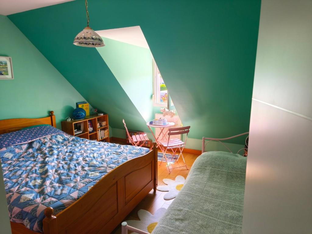a bedroom with a bed and a green wall at Sous le pommier in Douvres-la-Délivrande