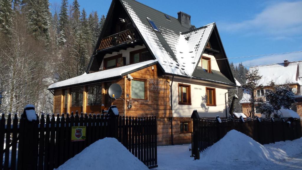 ザコパネにあるHomestay Srebrny Potokの雪の中に黒柵を敷いた木造家屋