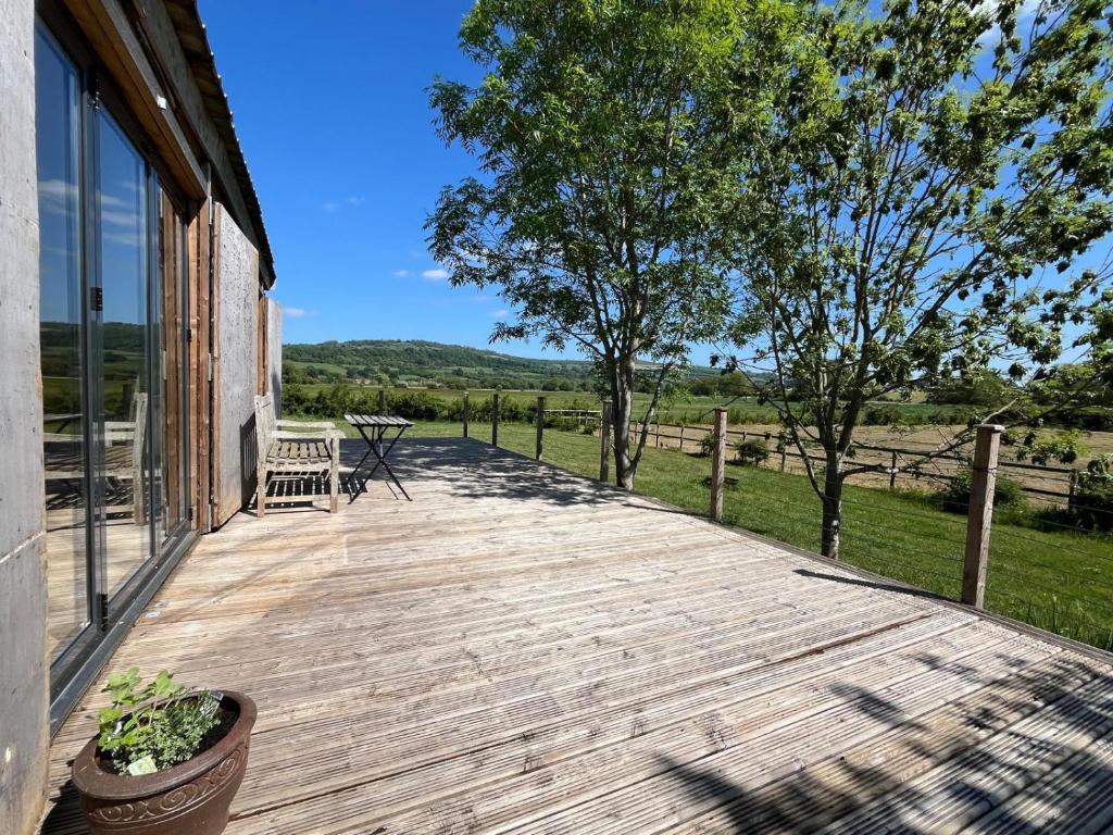a wooden deck with a table and chairs on a house at Meadows - Eco Retreat in Bitton