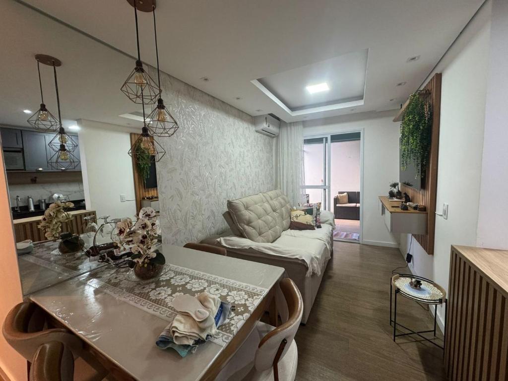 a kitchen and living room with a table and a couch at Apartamento Garden com churrasqueira área Gourmet in Bauru