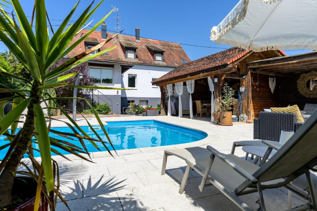 a swimming pool with a chair and a house at Chez Noëlle - Piscine in Sélestat