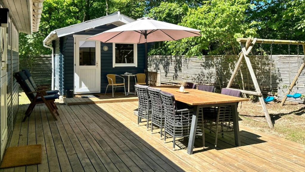 a wooden deck with a table and an umbrella at Cottage Near Forest And Beach in Glesborg