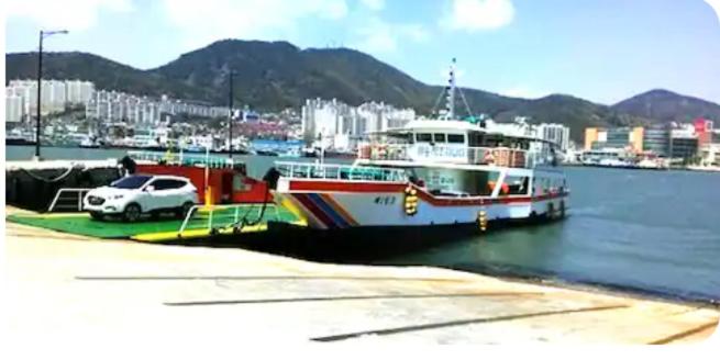 a car is parked next to a boat in the water at Kseashorehouse in Nŏmŏ