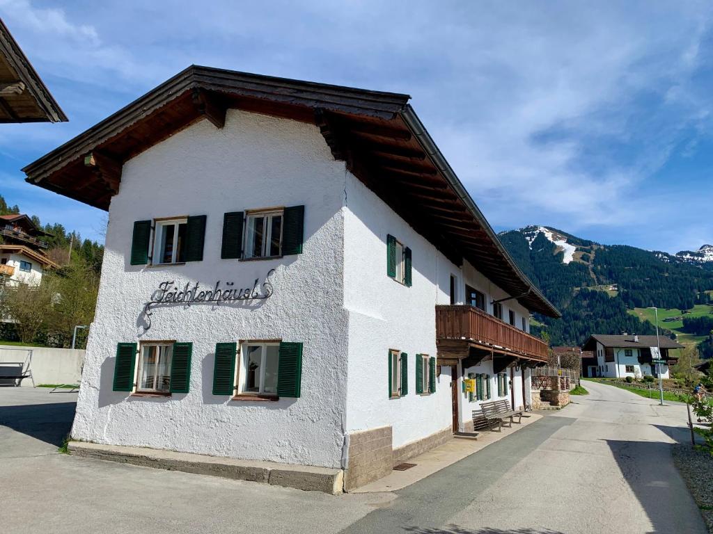 a building with green shuttered windows and a mountain at Feichtenhäusl app 2 in Westendorf