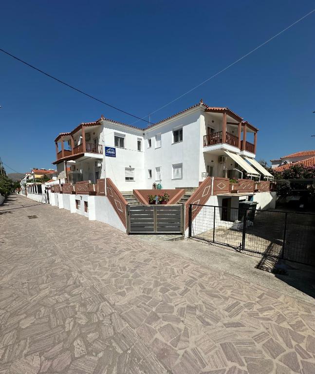 a white building with a fence in front of it at Joanna Rooms in Skala Eresou