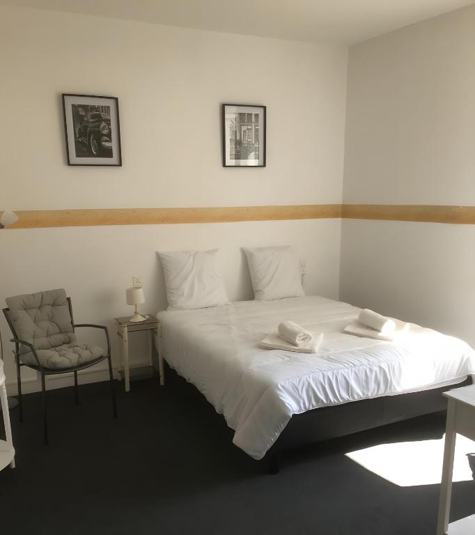 a bedroom with a large white bed and a chair at Acionna Résidence Studio 30 M² in Bourbonne-les-Bains