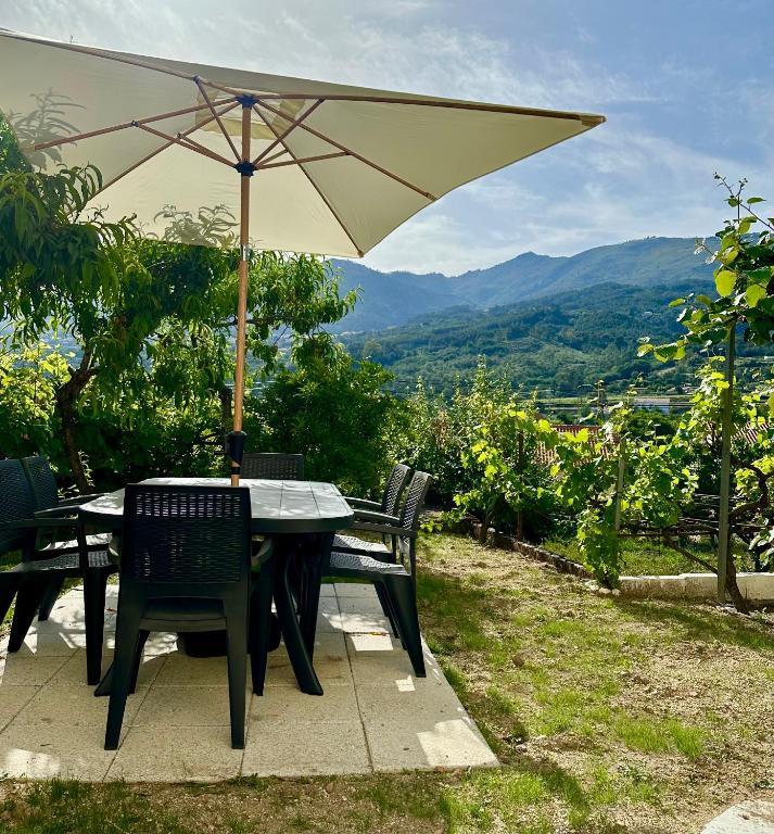 a table and chairs with an umbrella on a patio at O Jardim Mágico in Teixoso
