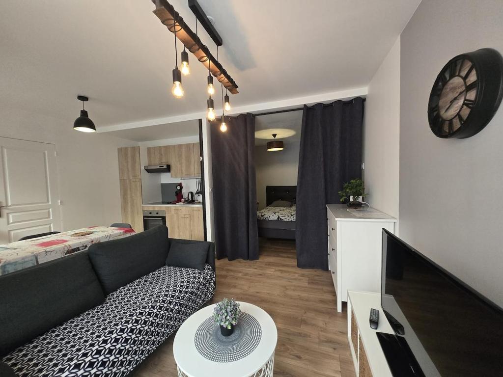 a living room with a couch and a tv and a bedroom at 1 Le Cocon Mosaïque Centre-ville in Ernée