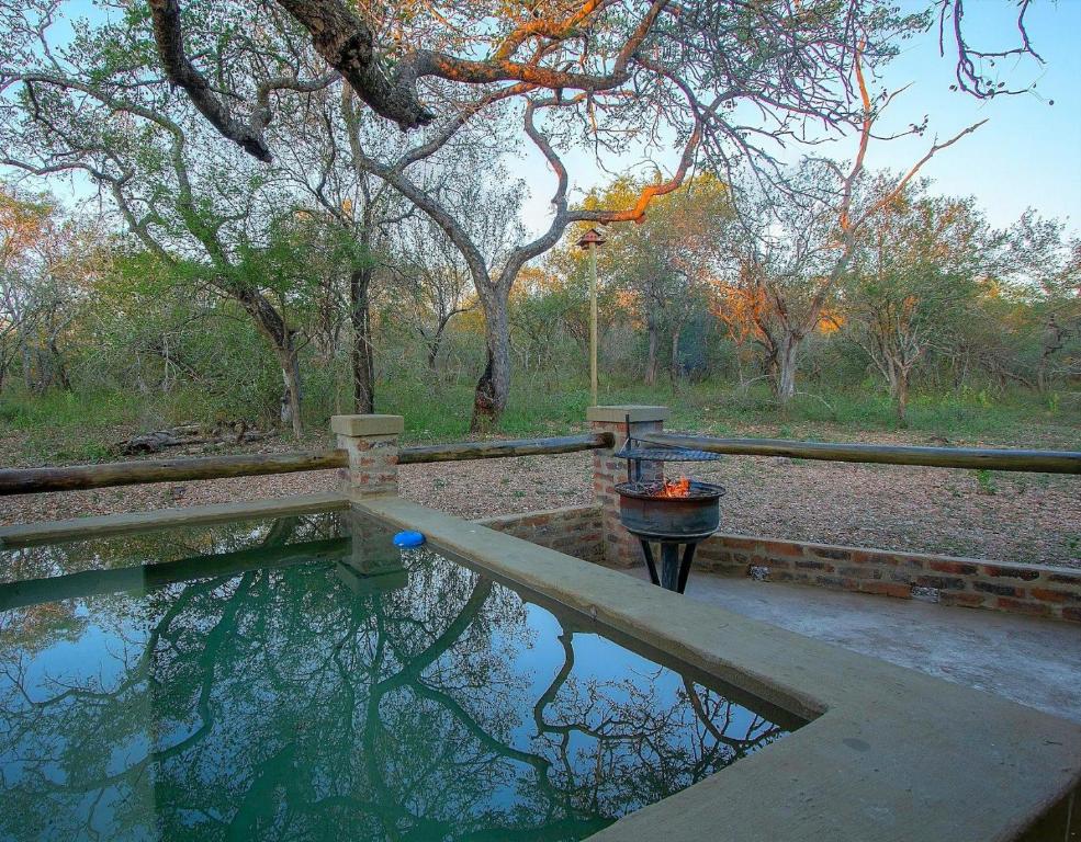 a pool of water with a fire hydrant and trees at Kruger's Retreat & Rest in Marloth Park
