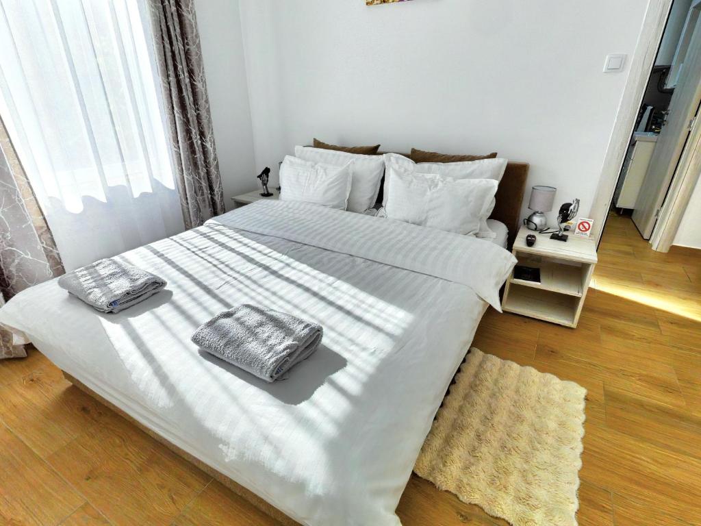 a bedroom with a large white bed with two towels on it at Apartman Dve lipe in Palić