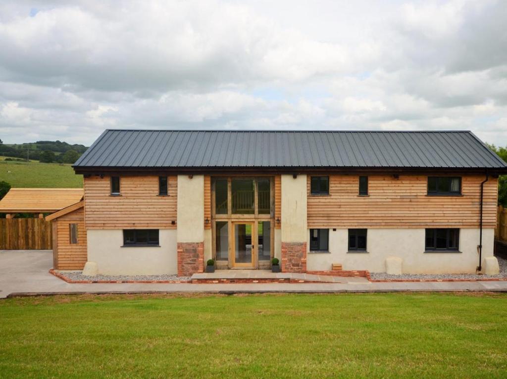 a wooden house with a black roof on a field at 5 Bed in Tiverton oc-48151 in Cadeleigh