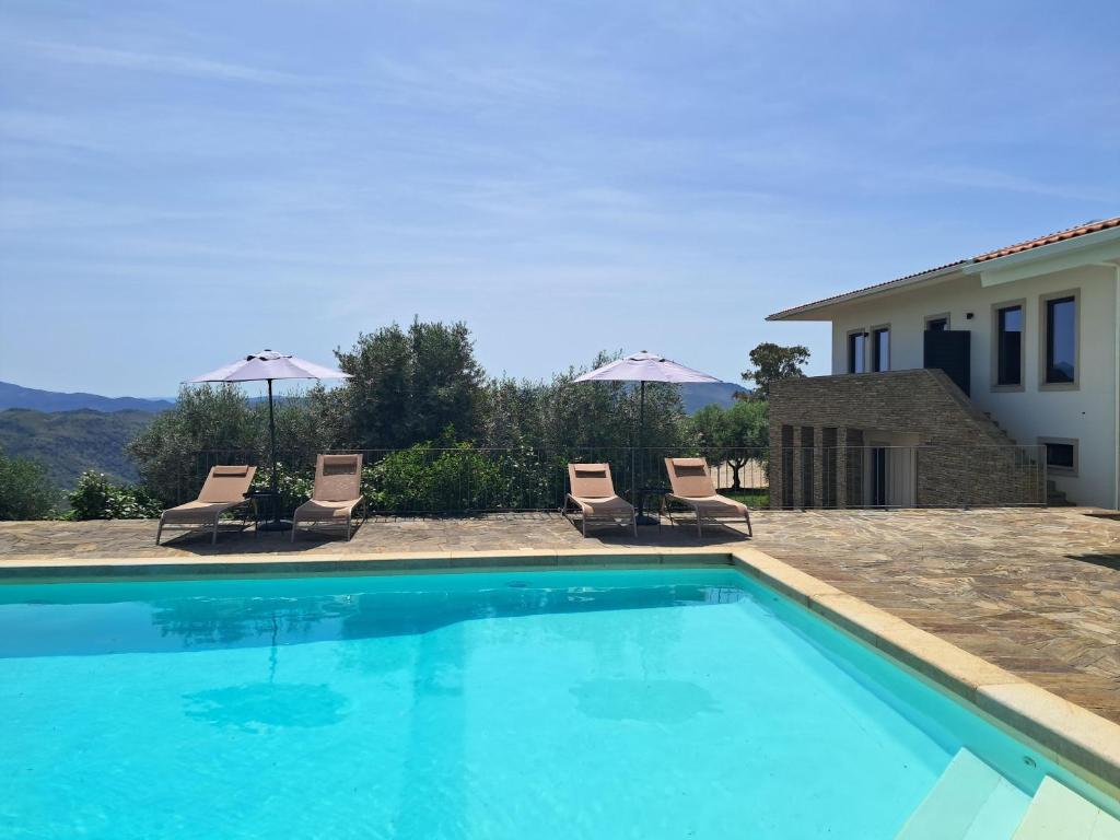 a swimming pool with lounge chairs and a house at Quinta Alto da Fraga in Vila Nova de Foz Coa