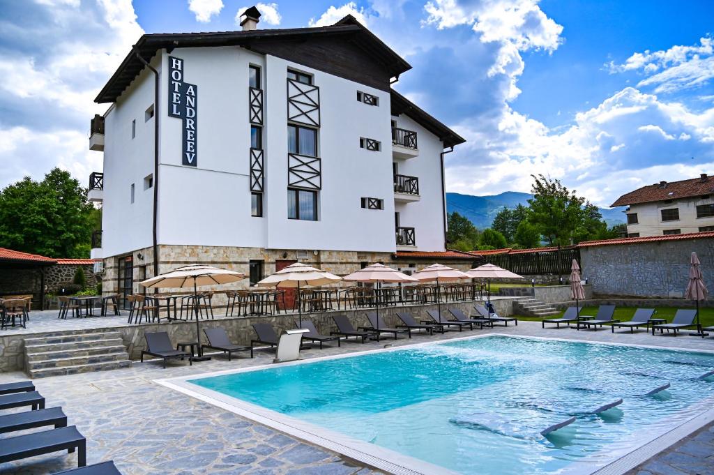a hotel with a swimming pool in front of a building at Family hotel Andreev in Dobrinishte