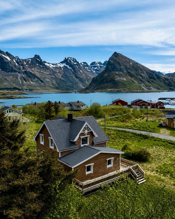 a house in a field with a lake and mountains at The Chess House Lofoten - Luxury Arctic Villa in Fredvang in Fredvang