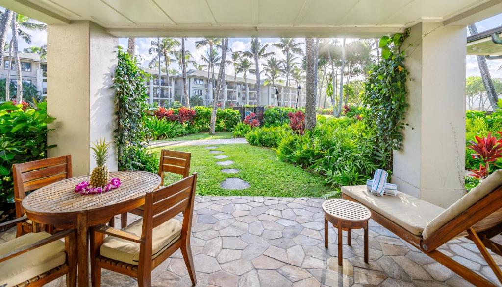 a patio with a table and chairs and a garden at 3-Bed Villa 115 at Turtle Bay in Kahuku